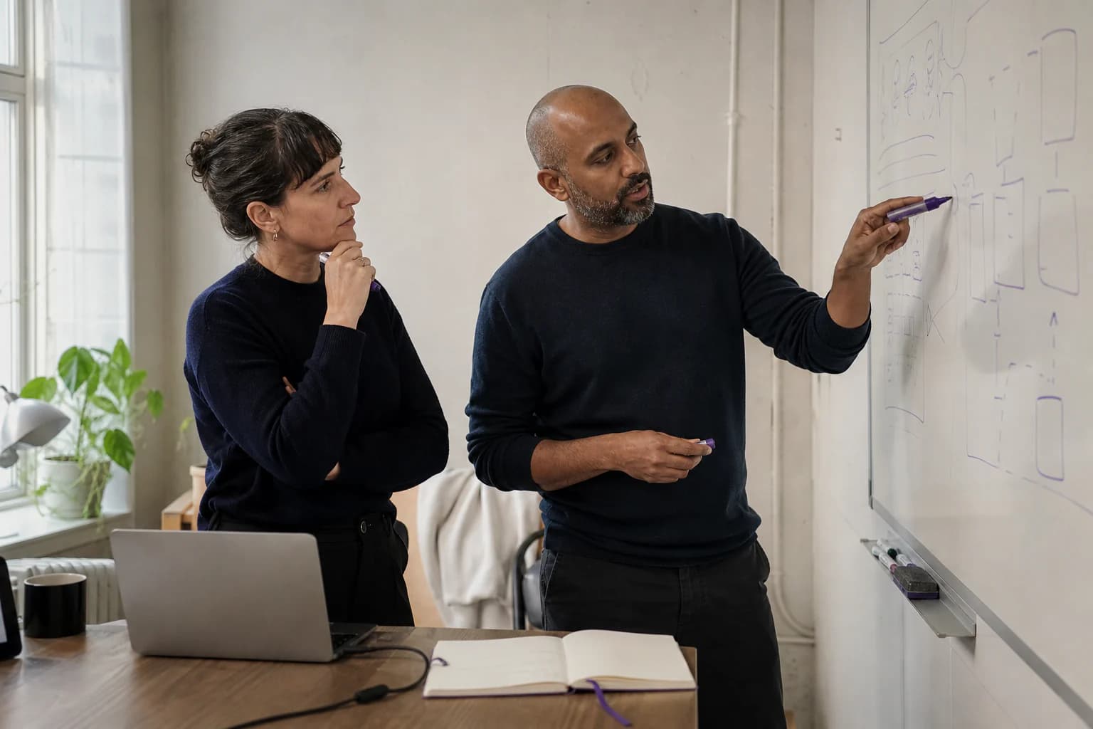 Two professionals evaluating technical options at a whiteboard